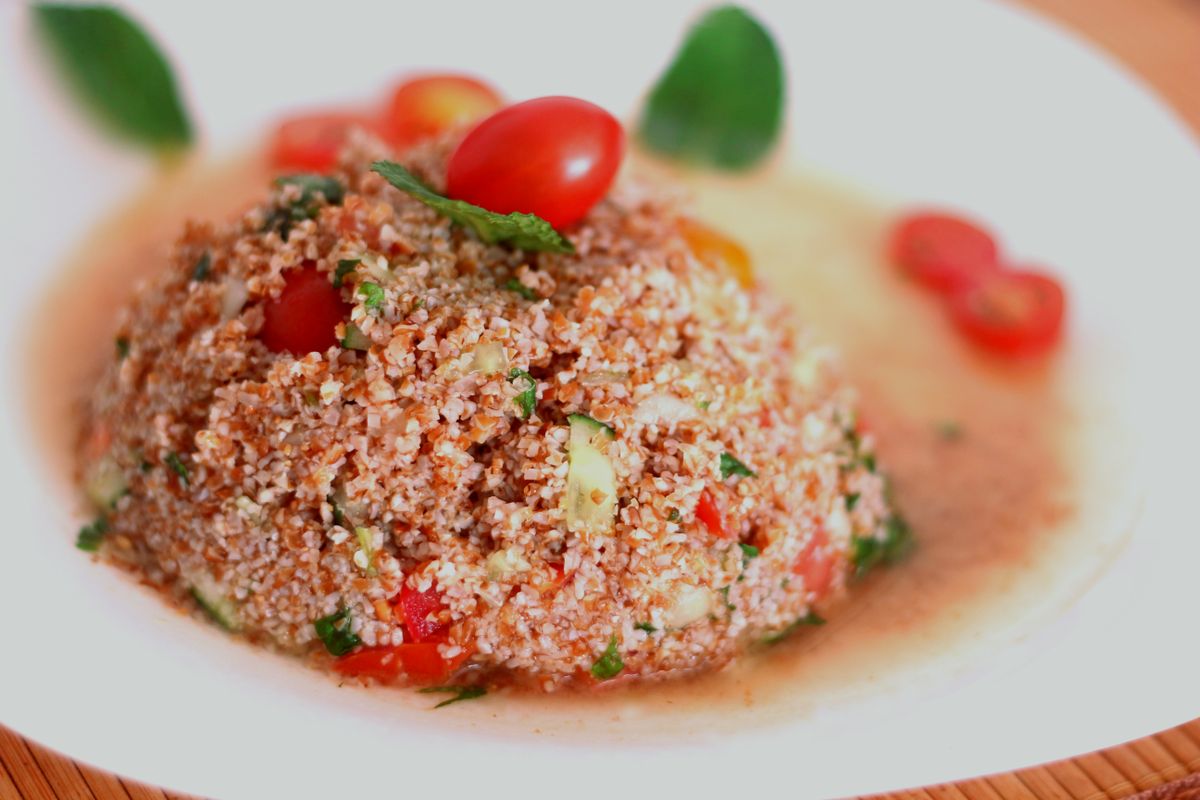 Mound of tomato-tinted bulgur salad with cherry tomatoes and mint in a white bowl