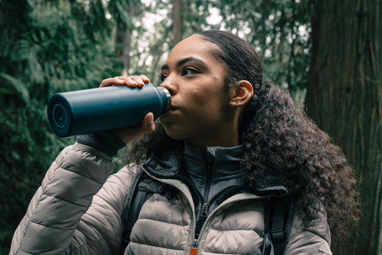 Woman In White Bubble Jacket Drinking From A Tumbler