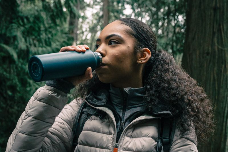 Woman drinking from a water bottle while hiking — photo by PNW Production on Pexels