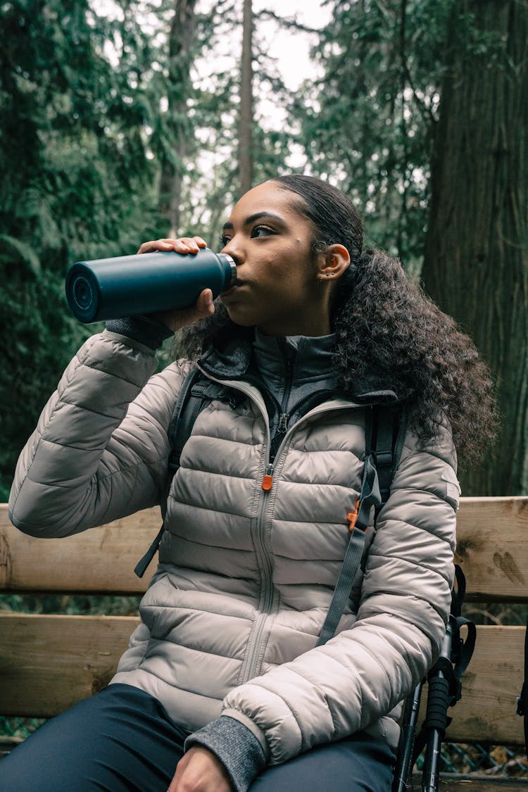 Woman In White Bubble Jacket Drinking From A Tumbler