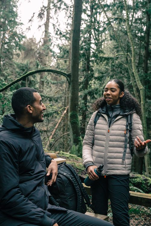 Free A happy duo enjoying a conversation in the woods, showcasing outdoor adventure spirit. Stock Photo