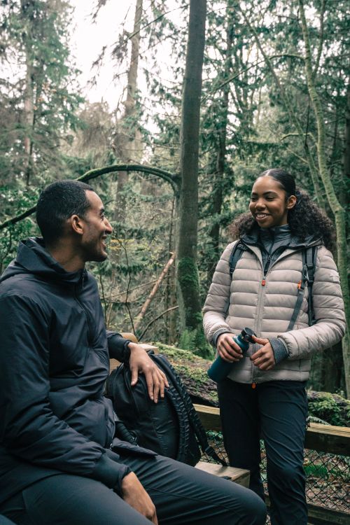 Free Two young adults enjoying a conversation on a forest hike, smiling and relaxed. Stock Photo