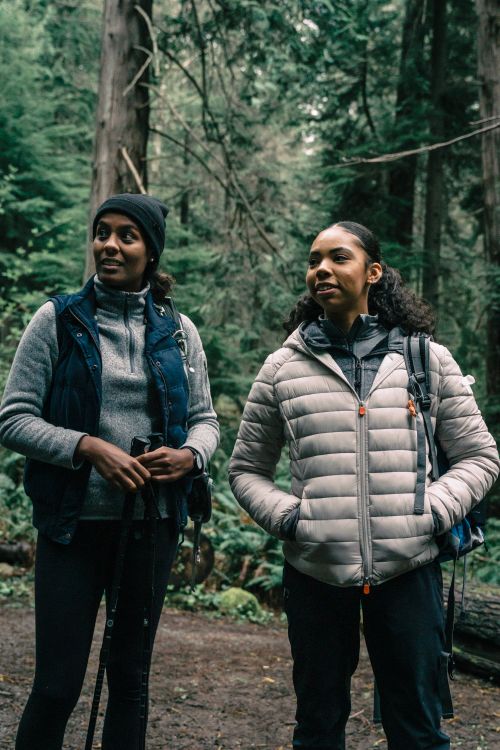 Free Two women enjoying a hike through a dense, verdant forest, equipped with trekking gear. Stock Photo