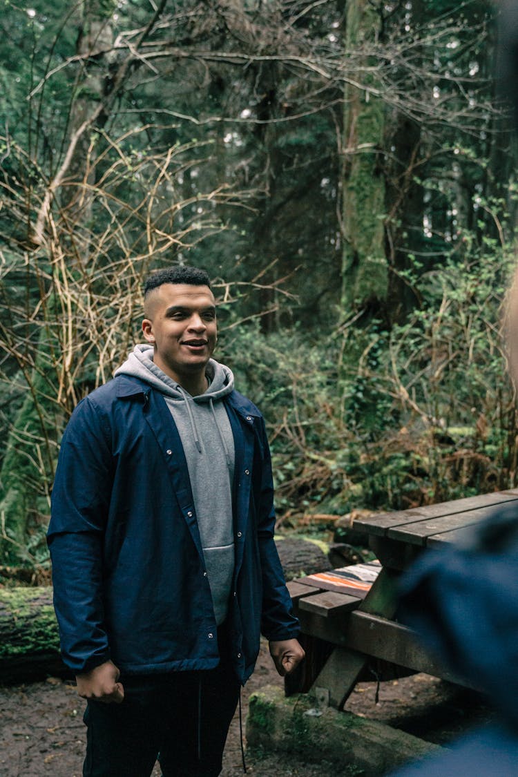 Man In Blue Jacket Standing Near A Picnic Bench