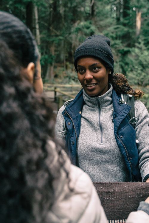 Free Two women in outdoor gear having a friendly conversation in a forest setting. Stock Photo
