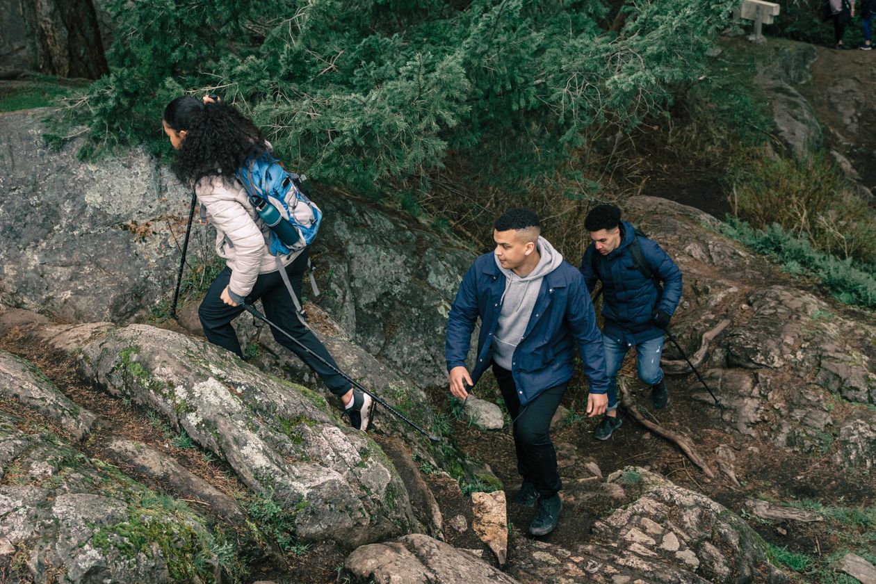 People hiking on a wooded forest trail in outdoor clothing