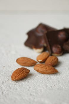 Almonds on a textured surface with dark chocolate in the background. Perfect for food photography.