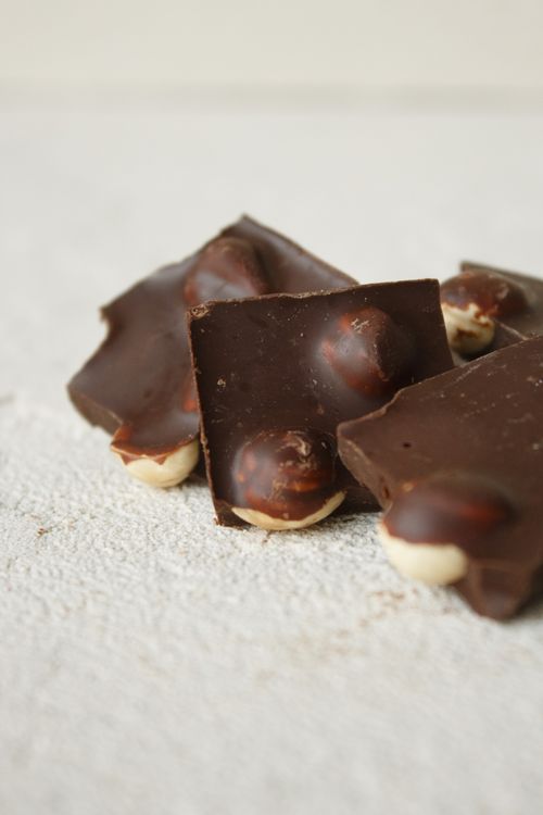 Free Close-up of dark chocolate pieces with hazelnuts on a textured surface. Stock Photo