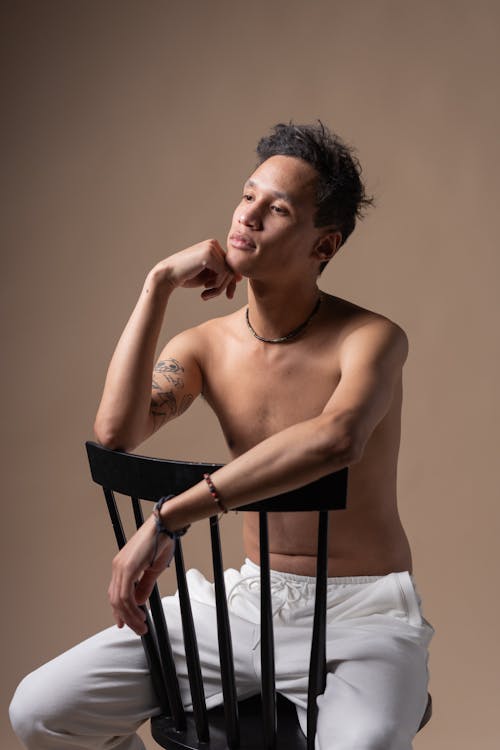 A Topless Man Sitting on a Chair