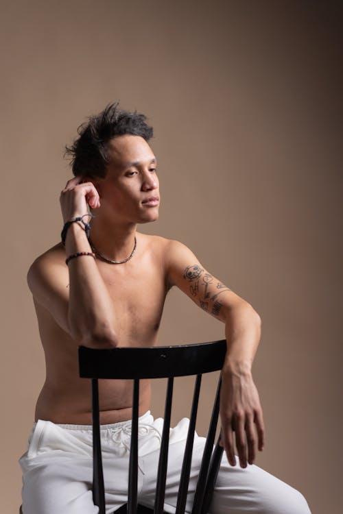 A Topless Man Sitting on a Chair