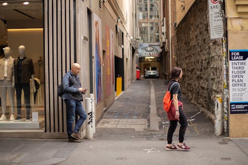 People Walking on the Sidewalk Near the Alleyway