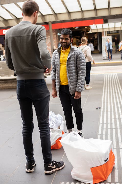 Men Standing on the Concrete Pavement Near Plastic Bags