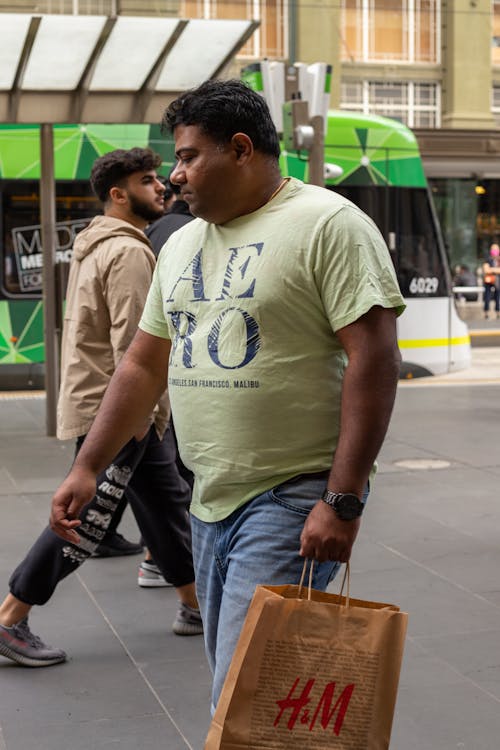 A Man Holding a Paper Bag on the Sidewalk