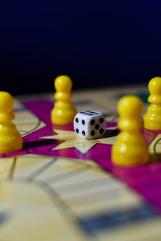 Close-up of a vibrant board game featuring yellow pawns and a dice on a colorful surface.