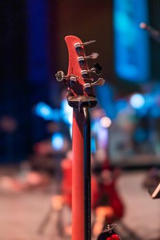 Headstock of modern electric guitar with tuning machines in shiny light at dusk on blurred background