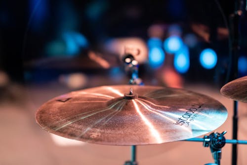Cymbals with shiny surface and bell in center on stage with artificial lights on blurred background