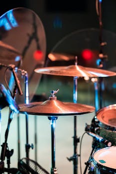 Drums and cymbals with glowing surface and microphones on stage in dim light on blurred background
