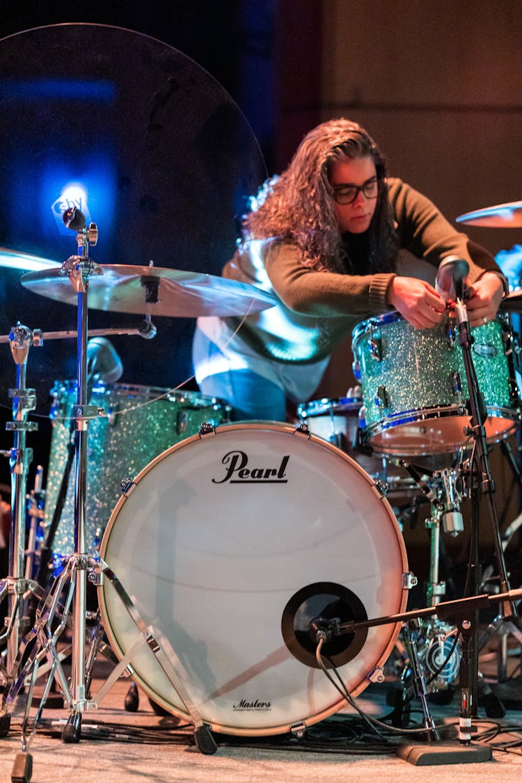 Woman Adjusting Mic Near Drums On Stage