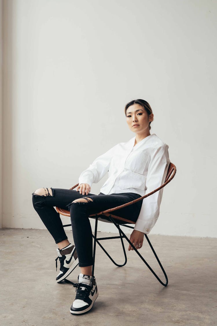 Serious Asian Woman Sitting In Stylish Armchair