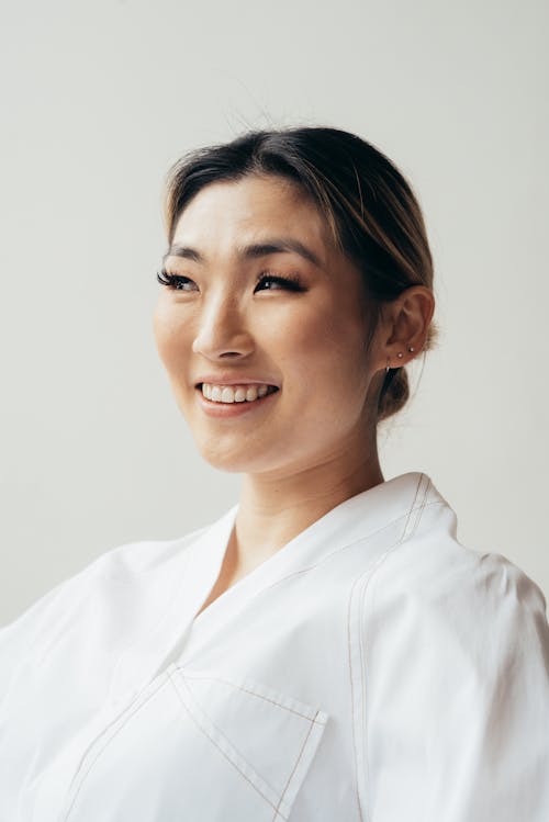 Positive Asian woman wearing white blouse in studio