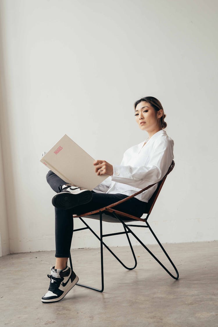 Confident Asian Woman With Opened Book In Studio