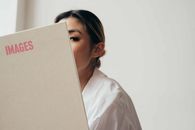 Crop ethnic female with brown eyes reading hardcover book in studio and looking at camera