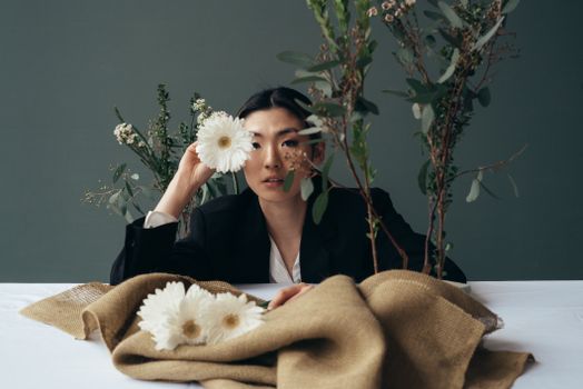 Confident Asian woman showing bud of gerbera