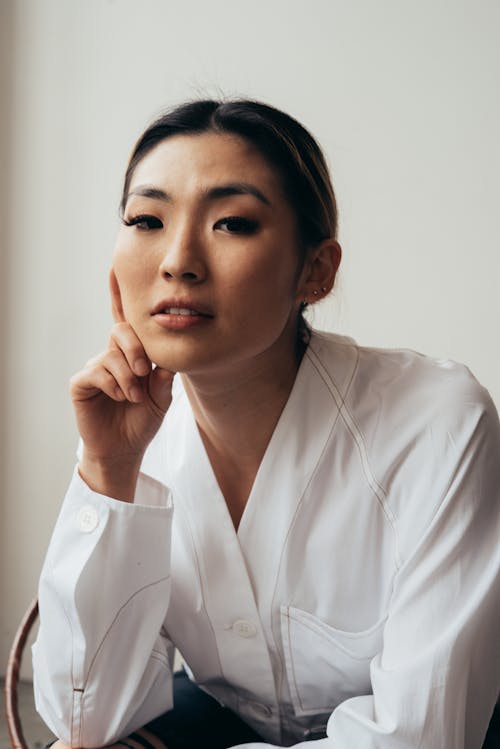 Elegant Asian woman touching face on white background
