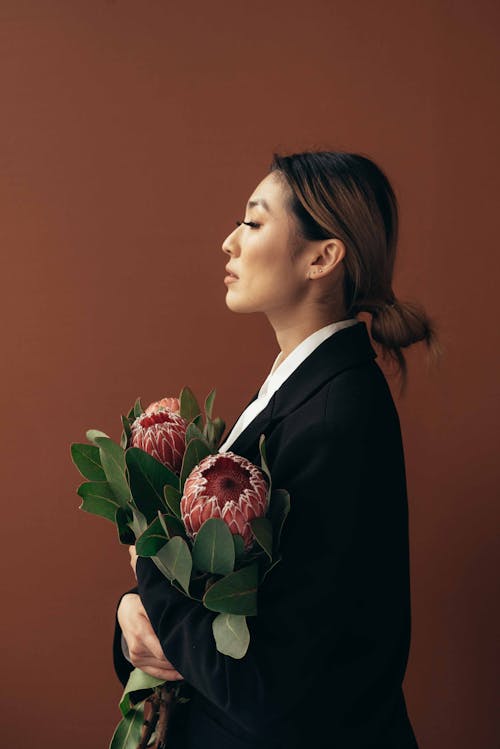 Dreamy elegant Asian woman with bunch of Protea flowers