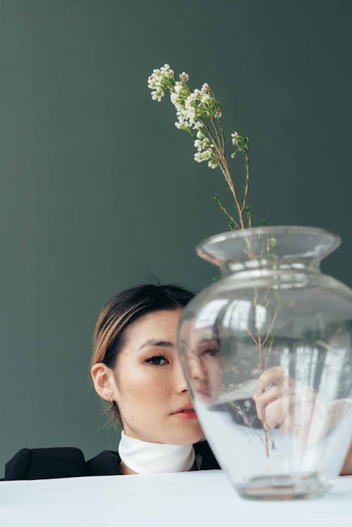 Asian woman near vase with fresh water and delicate flowers