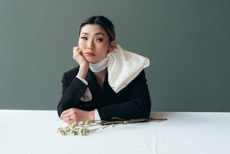 Bored Asian Woman Pondering At Table With Thin Branch