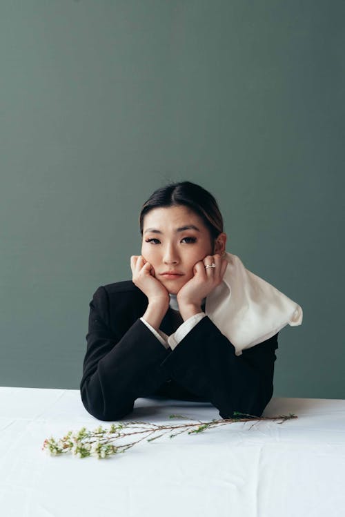 Young Asian woman at table with fragile blooming flowers