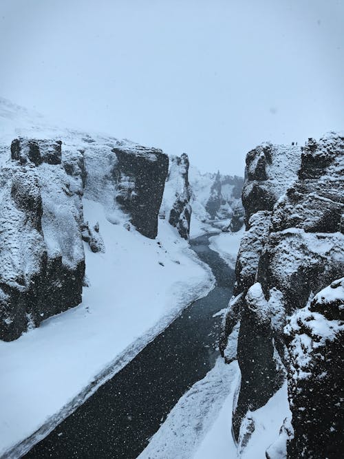 A River between Snow-Covered Rocky Cliffs