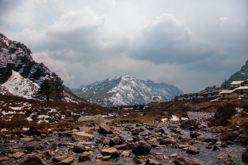 Free Rocks on frozen ground near village with houses located in mountainous terrain covered with snow against overcast sky on winter day Stock Photo