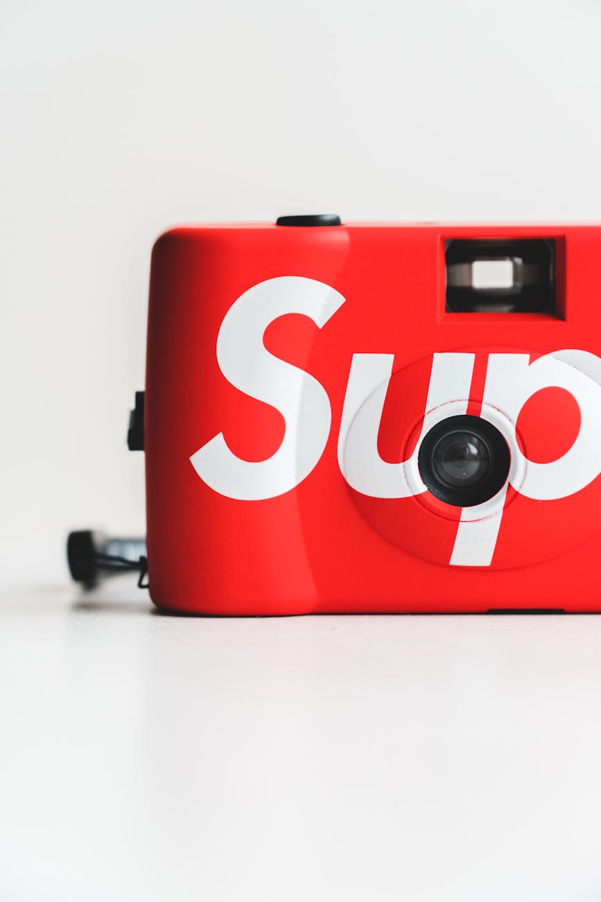 Isolated retro photo camera of red color with inscription placed against white background