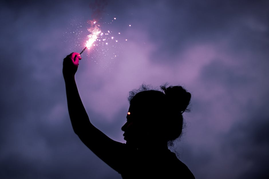 Anonymous woman with sparkler against dark sky