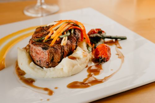 Free From above of palatable grilled meat and veggies served on white ceramic plate with potato puree and sauce in restaurant Stock Photo