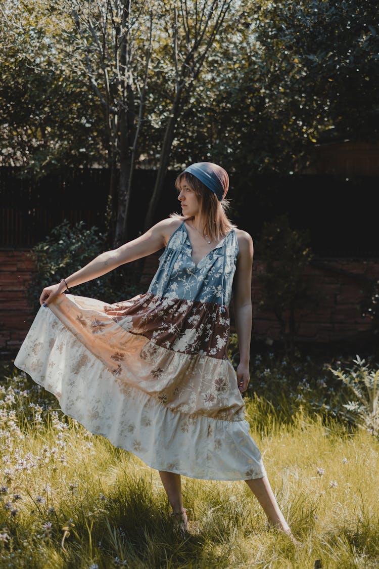 Young Stylish Lady Holding Hem Of Maxi Dress On Meadow In Countryside