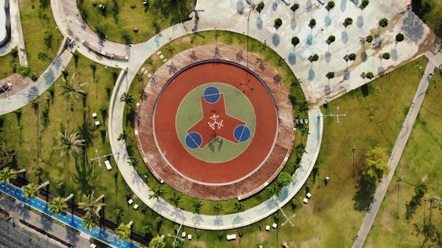 Drone shot capturing a symmetrical circular basketball court in Muratpaşa, Antalya, surrounded by greenery.