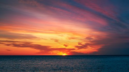 Free A vivid sunset over the ocean with colorful clouds creates a breathtaking seascape scene. Stock Photo