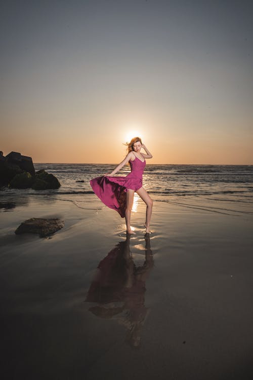 Woman in a Pink Dress Posing in Sea Water at Dusk