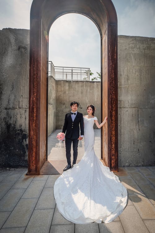 Free A Newlywed Couple Standing Under an Arched Gateway Stock Photo
