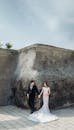 A Newlywed Couple Standing in Front of a Concrete Wall