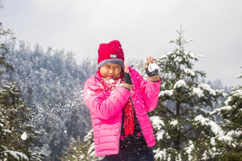 Free Young woman playing with snow in a snowy forest, enjoying winter outdoors. Stock Photo