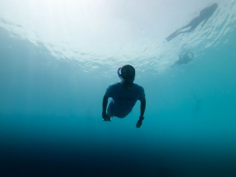 A snorkeler navigates the clear blue waters of the Maldives, capturing an underwater adventure.