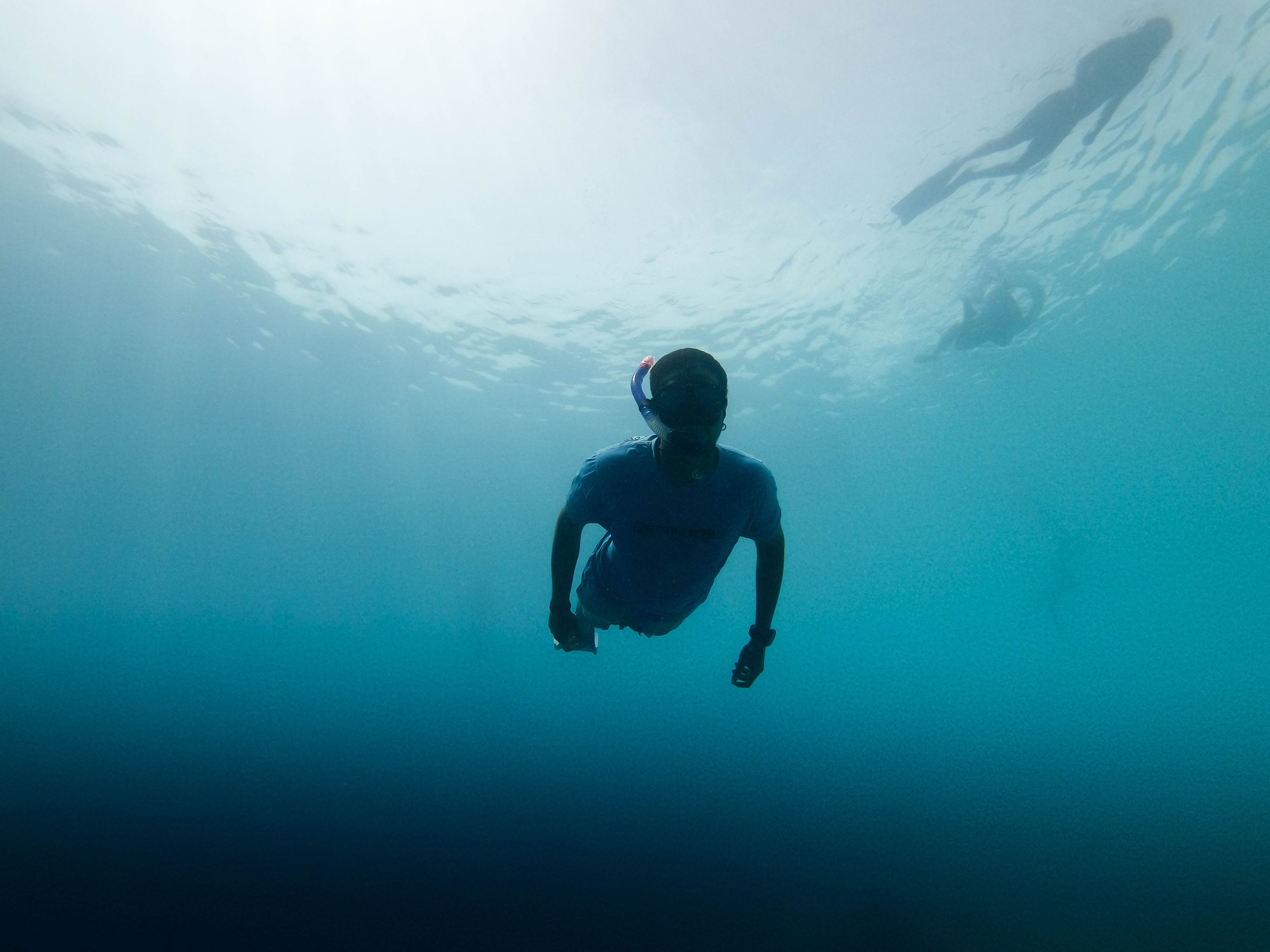 A snorkeler navigates the clear blue waters of the Maldives, capturing an underwater adventure.