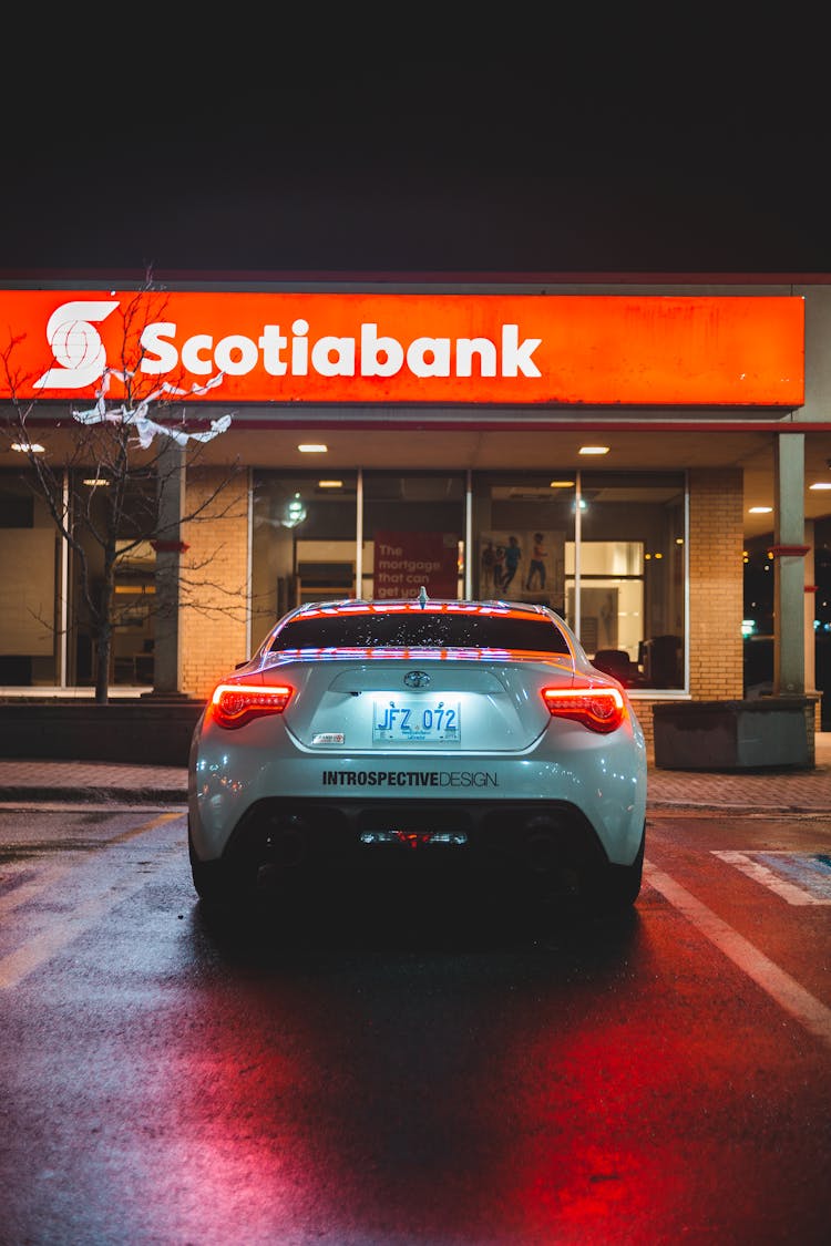 Stylish Car Near Bank Building At Night