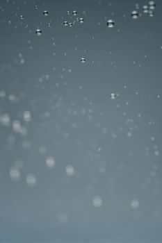 Close-up of water droplets on a smooth gray surface with a blurred effect.