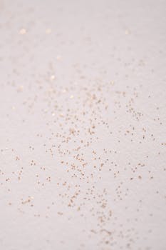 Close-up view of shimmering gold glitter scattered on a smooth white background. Perfect for abstract and texture designs.
