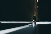 在一个黑暗的房间里，一座孤独的雕像沐浴在变幻的光线中，投下戏剧性的阴影